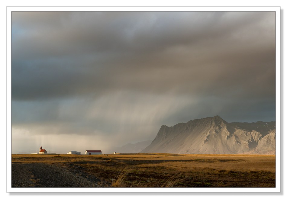 Landscape Photograph, Fáskrúðarbakkakirkja church with rain sweeping past towards the mountains, Iceland, waiting for the light